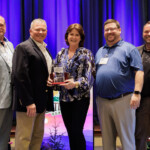 Karla Knisley, project specialist for VolCorp, receives the Hall of Fame Award. She is pictured with Fred Robinson, president and CEO of the League, her husband and son, and Jeff Merry, president and CEO of VolCorp.