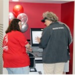An Enrichment Federal Credit Union member learns more from an EFCU in-person teller during the Northshore Branch Grand Reopening about how new Interactive Teller Machines (ITM) work and how they can complete a wider range of transactions on the machines.