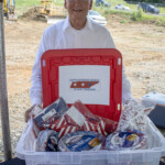 United Veteran’s Council Breakfast Project Chair, Buzz Buswell, accepts a $1,000 Community Enrichment donation and a bin overflowing with supplies from Enrichment Federal Credit Union during the groundbreaking ceremony on Wednesday, July 30.