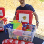 Brickey-McCloud Elementary School Assistant Principal, Wes Adcock, accepts a $1,000 Community Enrichment donation and a bin overflowing with supplies from Enrichment
Federal Credit Union during the groundbreaking ceremony on Wednesday, July 30.