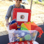 Halls Elementary School Principal, Jamey Romig, accepts a $1,000 Community Enrichment donation and a bin overflowing with supplies from Enrichment Federal Credit Union during the
groundbreaking ceremony on Wednesday, July 30.