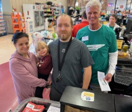 David LeVeau, president and CEO of Northeast Community Federal Credit Union, awards free groceries to a young family at the Food City in Elizabethton.